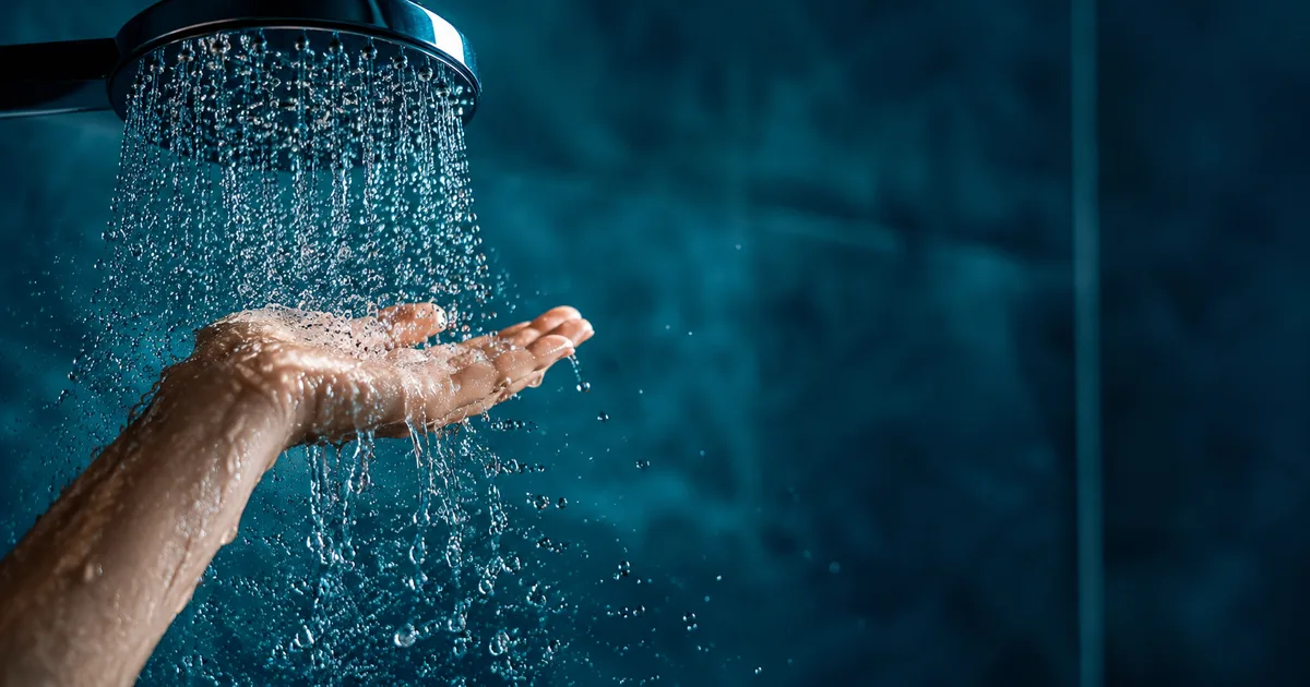 Mano bajo el chorro de la ducha con agua corriendo
